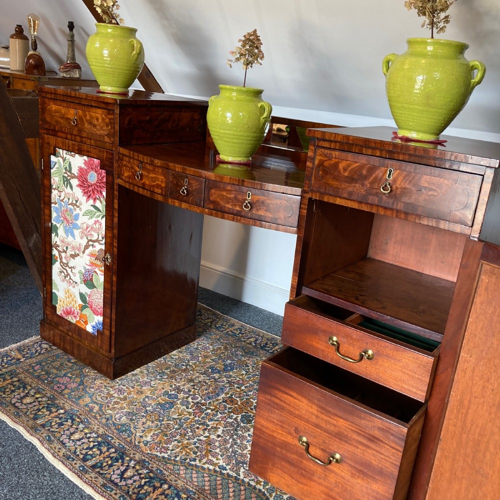 A late Georgian mahogany pedestal sideboard featuring two outer pedestals with floral fabric panels, central drawers, and warm flame mahogany wood grain. View VI