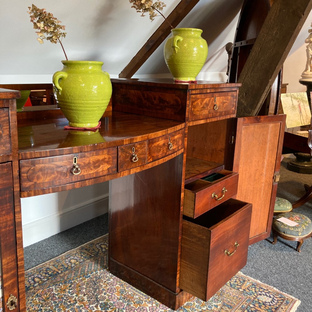 A late Georgian mahogany pedestal sideboard featuring two outer pedestals with floral fabric panels, central drawers, and warm flame mahogany wood grain. View VII