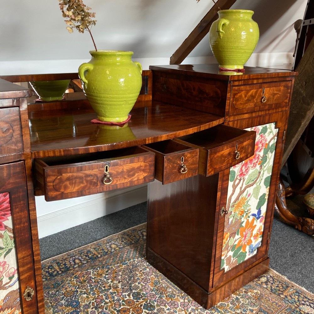 A late Georgian mahogany pedestal sideboard featuring two outer pedestals with floral fabric panels, central drawers, and warm flame mahogany wood grain. View VIII