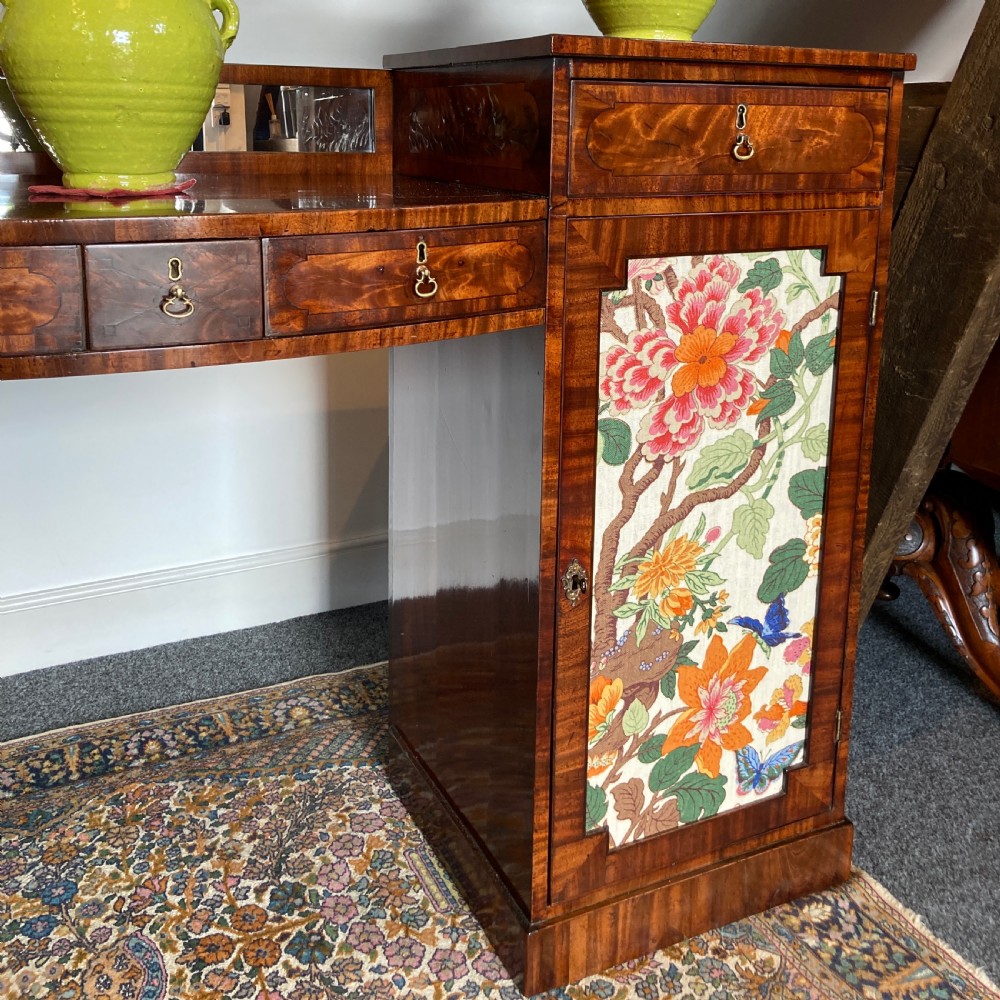 A late Georgian mahogany pedestal sideboard featuring two outer pedestals with floral fabric panels, central drawers, and warm flame mahogany wood grain. View IX