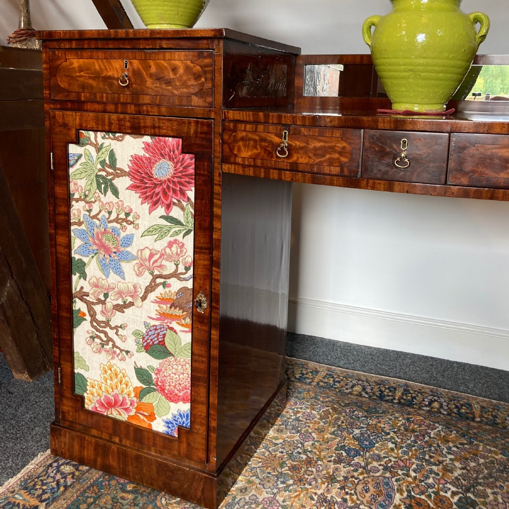 A late Georgian mahogany pedestal sideboard featuring two outer pedestals with floral fabric panels, central drawers, and warm flame mahogany wood grain. View X