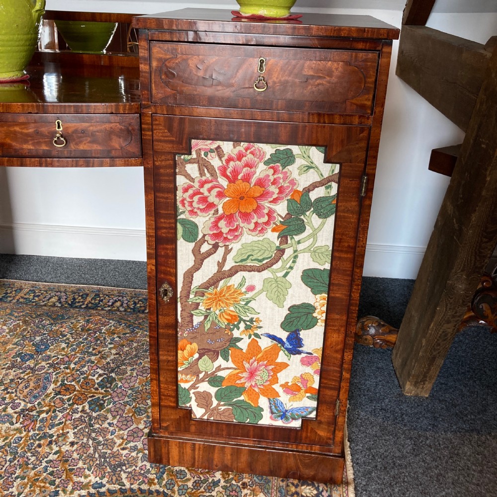 A late Georgian mahogany pedestal sideboard featuring two outer pedestals with floral fabric panels, central drawers, and warm flame mahogany wood grain. View XI