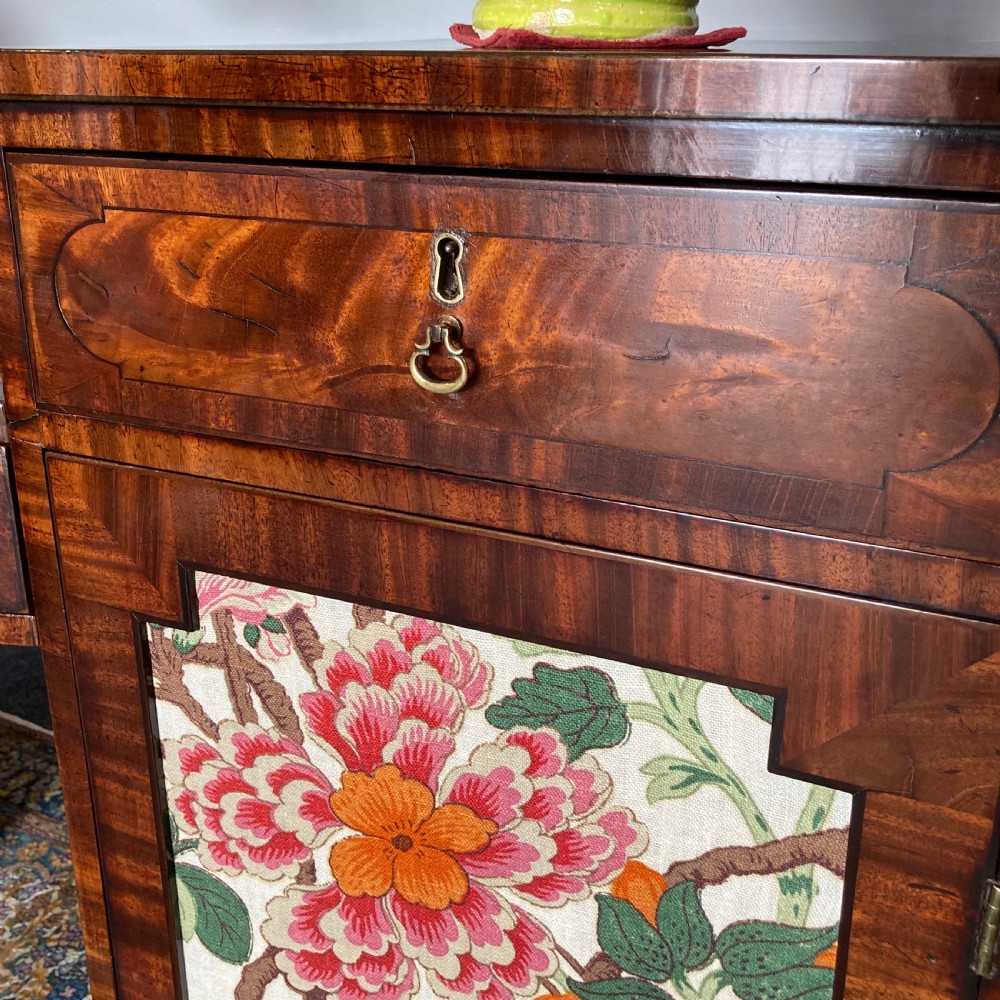 A late Georgian mahogany pedestal sideboard featuring two outer pedestals with floral fabric panels, central drawers, and warm flame mahogany wood grain. View XII