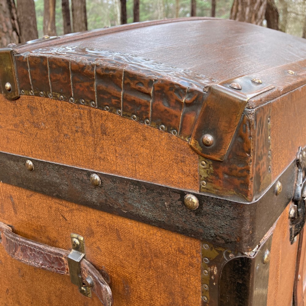 A late nineteenth-century domed steamer trunk with brown fabric covering, dark wooden banding, metal studs, and central brass lock hardware. View III