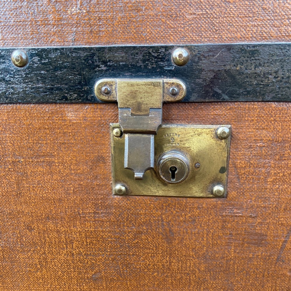 A late nineteenth-century domed steamer trunk with brown fabric covering, dark wooden banding, metal studs, and central brass lock hardware. View V