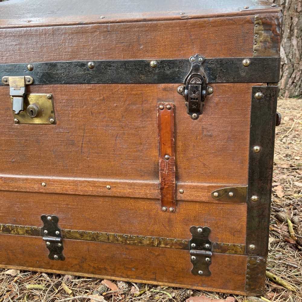 A late nineteenth-century domed steamer trunk with brown fabric covering, dark wooden banding, metal studs, and central brass lock hardware. View VI