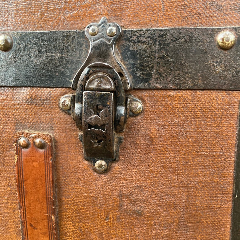 A late nineteenth-century domed steamer trunk with brown fabric covering, dark wooden banding, metal studs, and central brass lock hardware. View VII