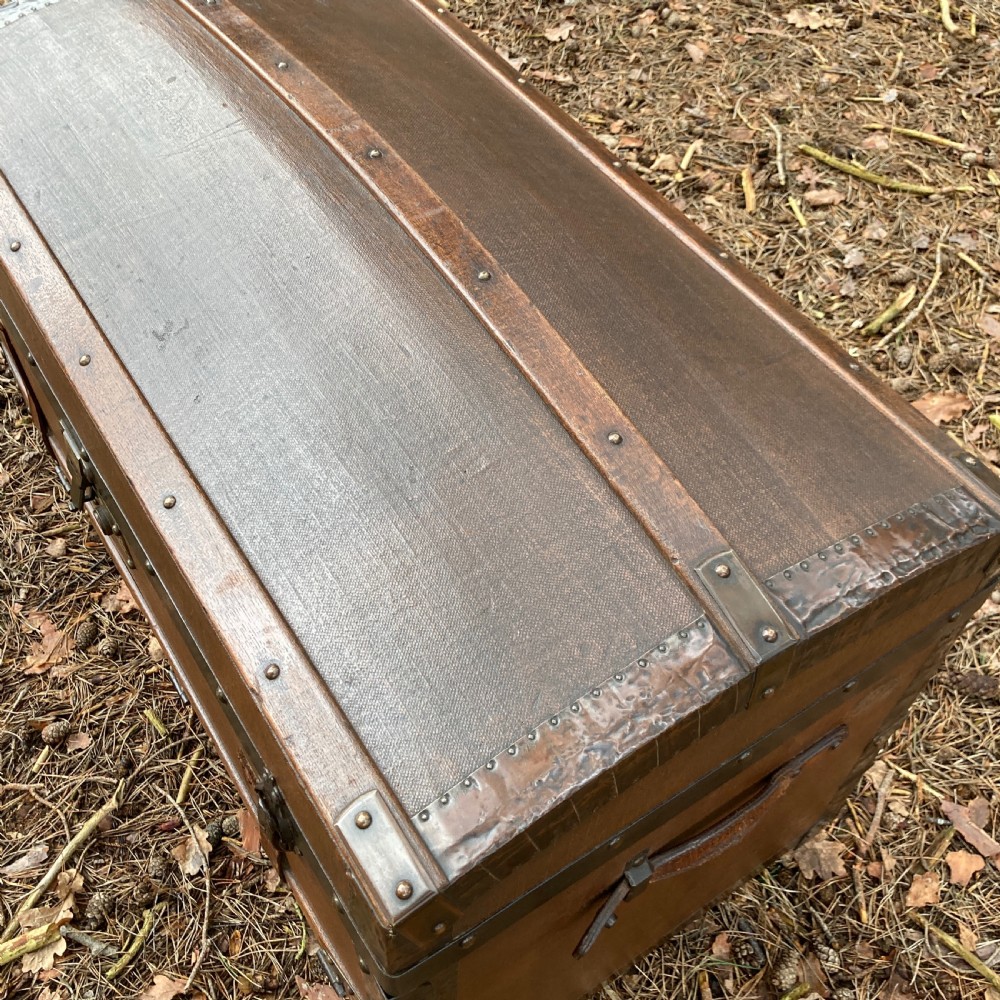 A late nineteenth-century domed steamer trunk with brown fabric covering, dark wooden banding, metal studs, and central brass lock hardware. View IX
