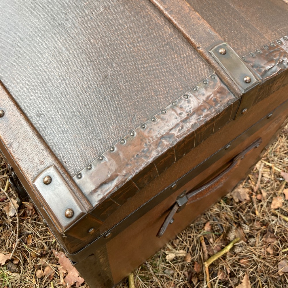 A late nineteenth-century domed steamer trunk with brown fabric covering, dark wooden banding, metal studs, and central brass lock hardware. View X