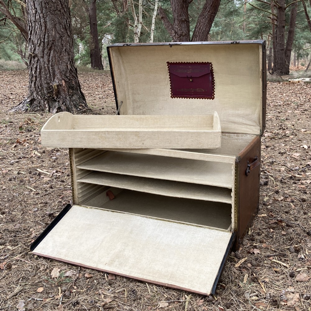 A late nineteenth-century domed steamer trunk with brown fabric covering, dark wooden banding, metal studs, and central brass lock hardware. View XVI