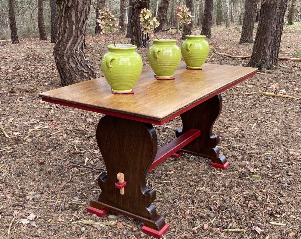 An antique oak and elm refectory table featuring dark trestle leg supports, a red painted stretcher with key joint, and a rectangular timber top. View III