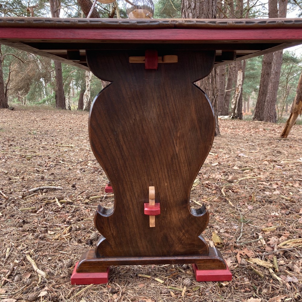 An antique oak and elm refectory table featuring dark trestle leg supports, a red painted stretcher with key joint, and a rectangular timber top. View XII