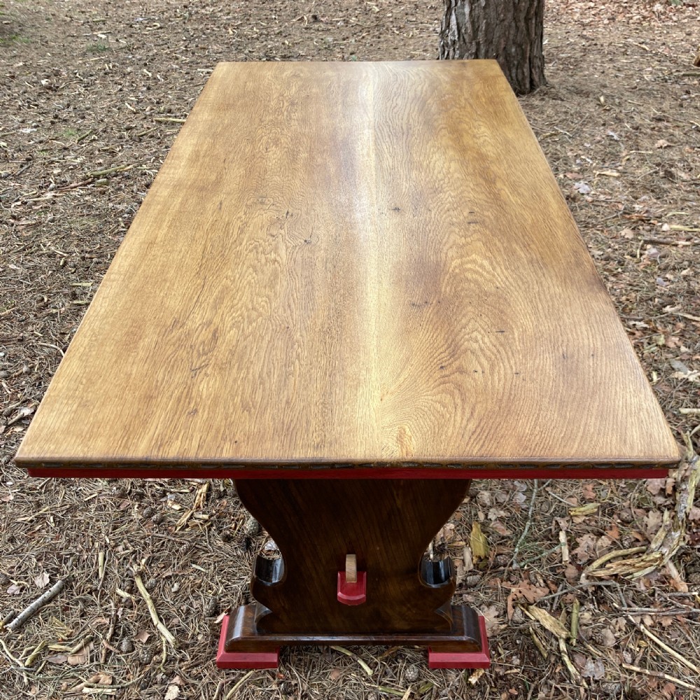 An antique oak and elm refectory table featuring dark trestle leg supports, a red painted stretcher with key joint, and a rectangular timber top. View XIII