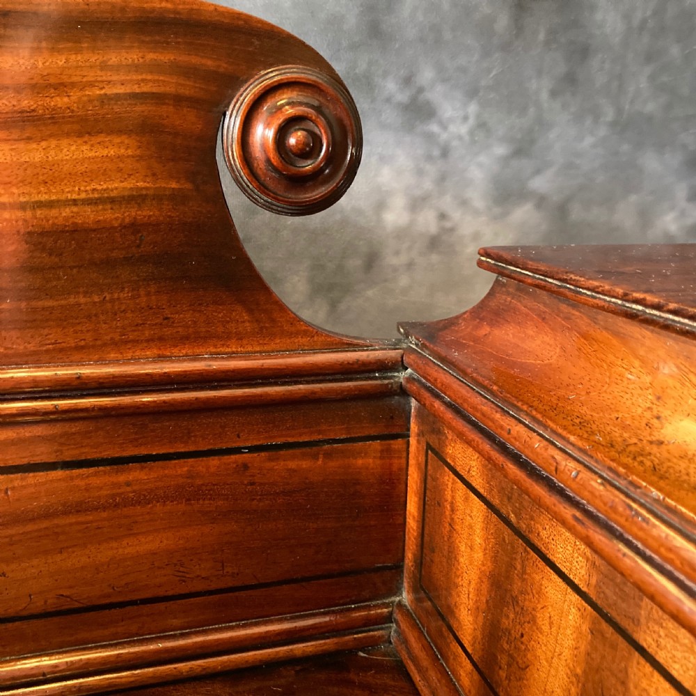 An Early Victorian flame mahogany pedestal sideboard with a central recessed drawer section, scrolled backboard, fluted pilasters, and twin side cupboard doors. View VIII