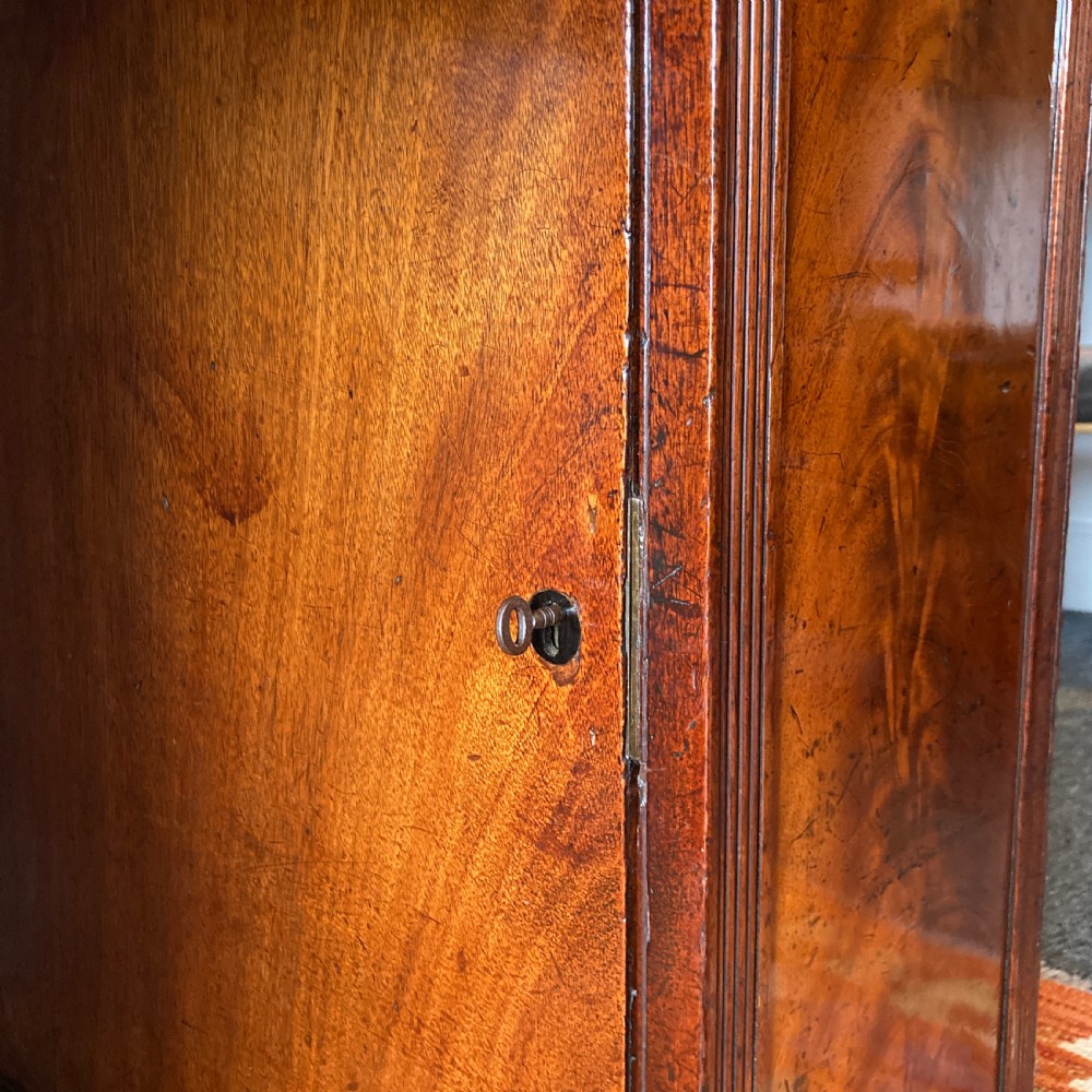 An Early Victorian flame mahogany pedestal sideboard with a central recessed drawer section, scrolled backboard, fluted pilasters, and twin side cupboard doors. View IX