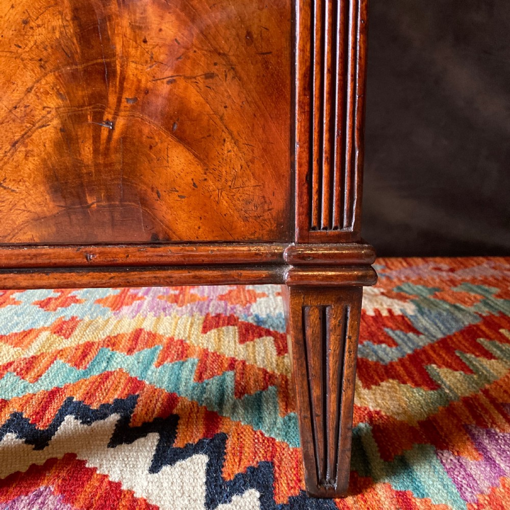 An Early Victorian flame mahogany pedestal sideboard with a central recessed drawer section, scrolled backboard, fluted pilasters, and twin side cupboard doors. View X