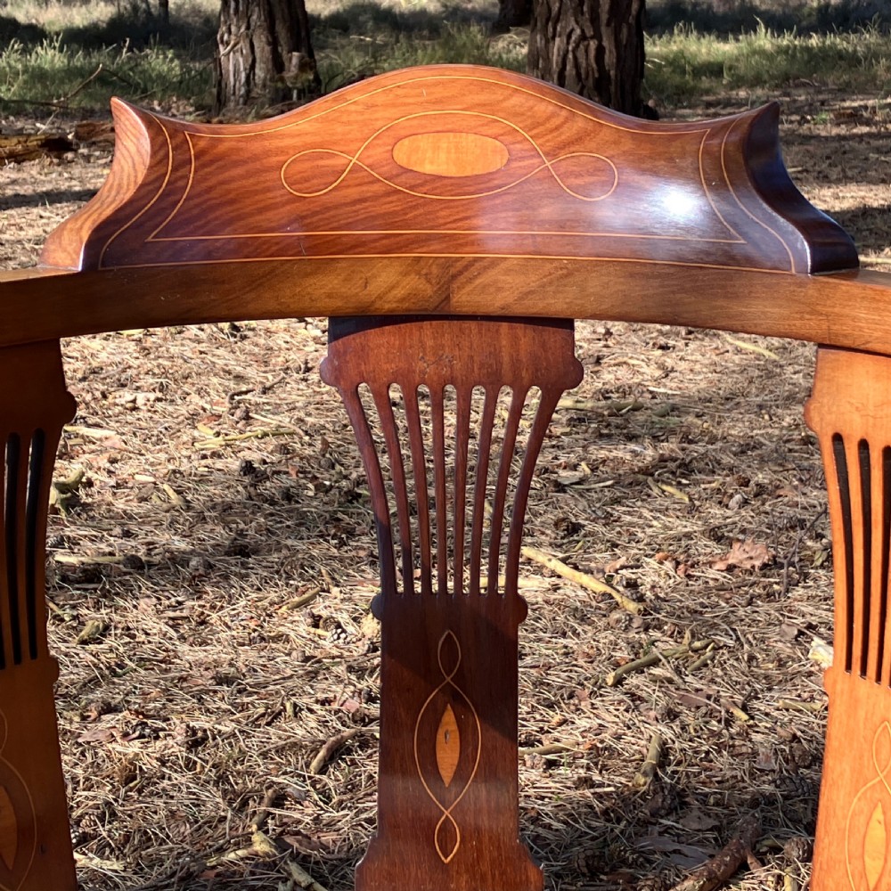 A pair of Edwardian mahogany corner chairs featuring curved top rails with marquetry inlay, vertical splats, upholstered patterned seats, and slender legs joined by stretchers. View III