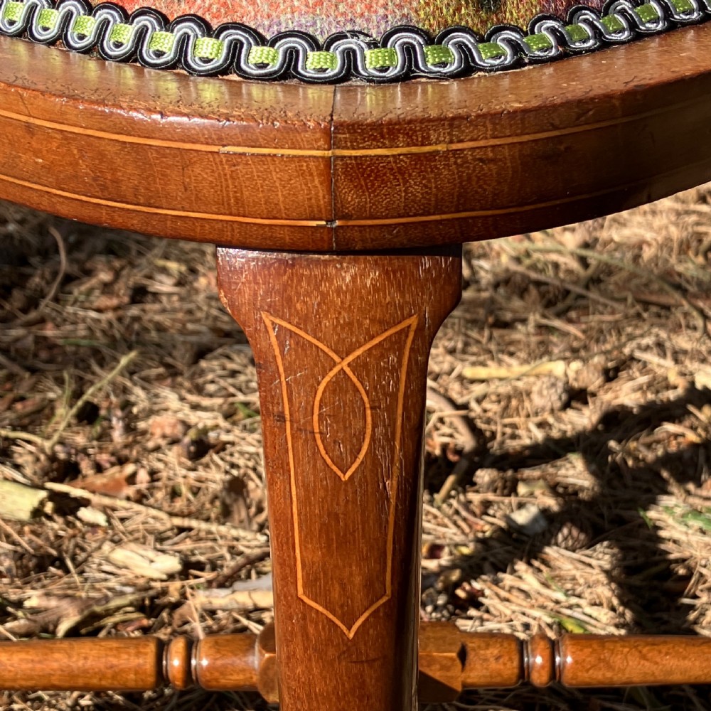 A pair of Edwardian mahogany corner chairs featuring curved top rails with marquetry inlay, vertical splats, upholstered patterned seats, and slender legs joined by stretchers. View V