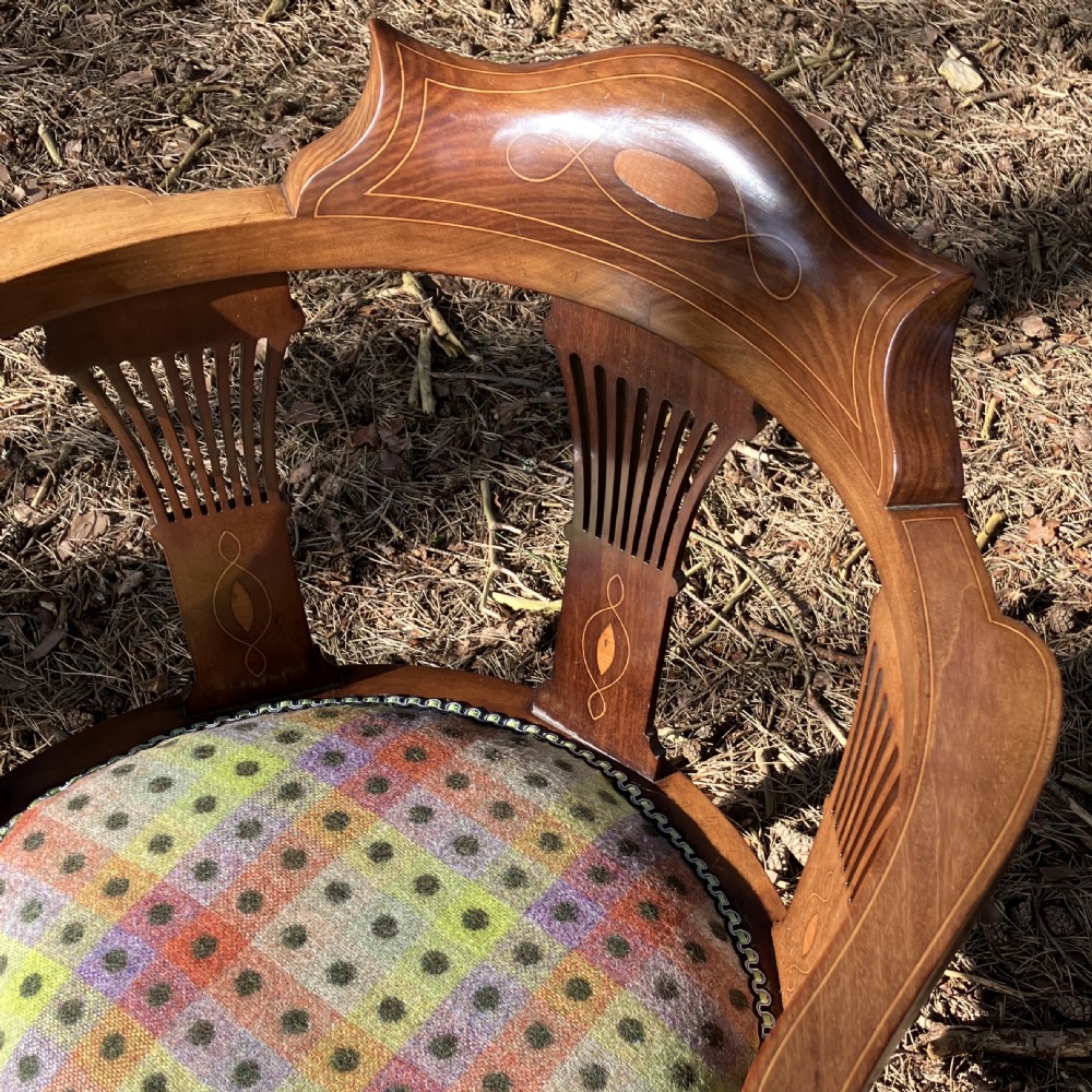 A pair of Edwardian mahogany corner chairs featuring curved top rails with marquetry inlay, vertical splats, upholstered patterned seats, and slender legs joined by stretchers. View VII
