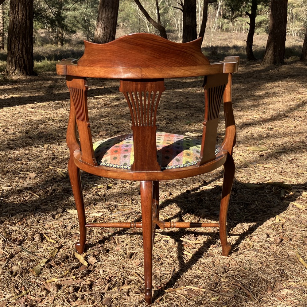 A pair of Edwardian mahogany corner chairs featuring curved top rails with marquetry inlay, vertical splats, upholstered patterned seats, and slender legs joined by stretchers. View VIII
