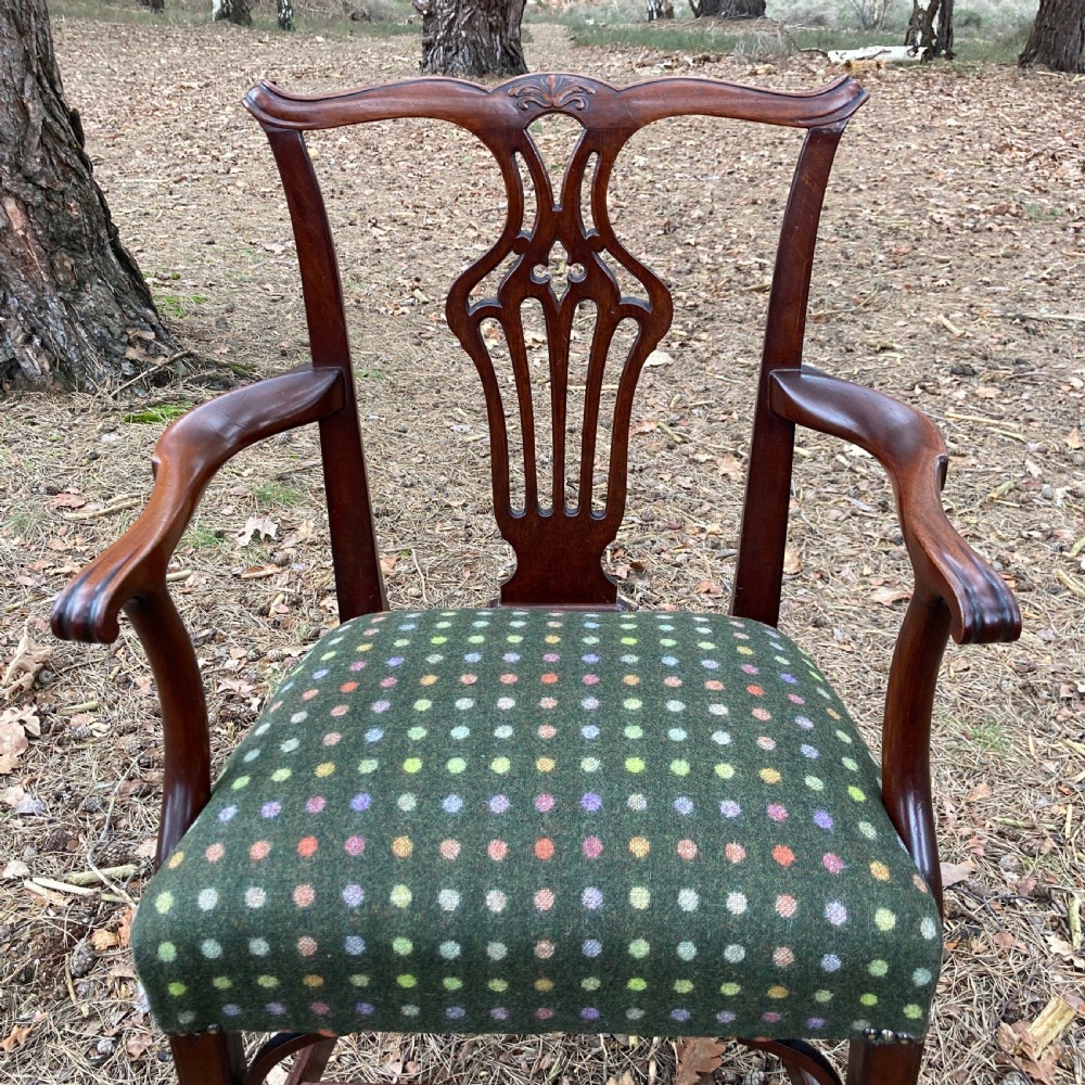 A pair of 1830s mahogany open armchairs featuring carved top rails, pierced splats, swept arms, and seats upholstered in a green patterned fabric. View V