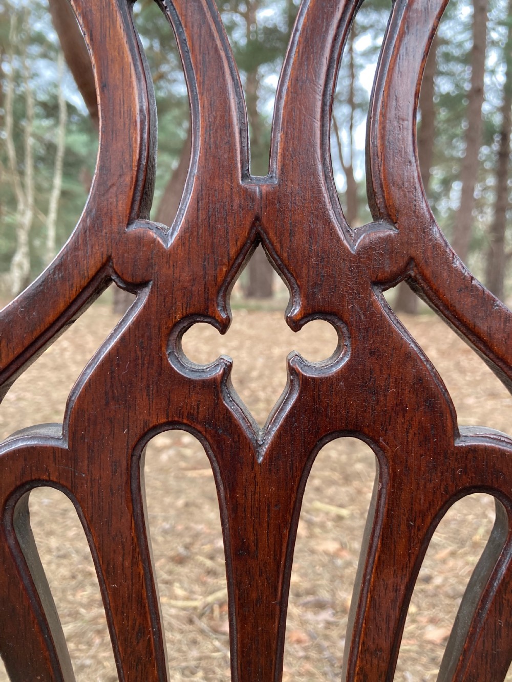 A pair of 1830s mahogany open armchairs featuring carved top rails, pierced splats, swept arms, and seats upholstered in a green patterned fabric. View VIII
