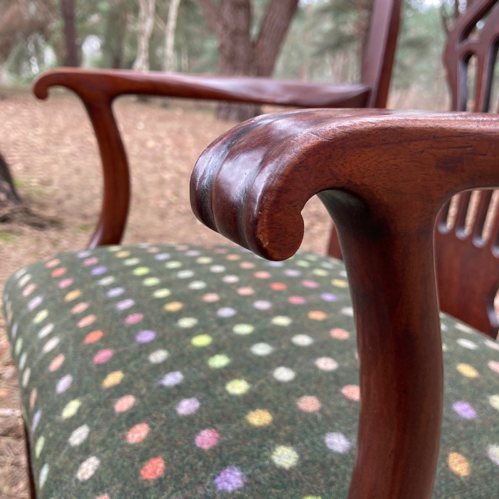 A pair of 1830s mahogany open armchairs featuring carved top rails, pierced splats, swept arms, and seats upholstered in a green patterned fabric. View X
