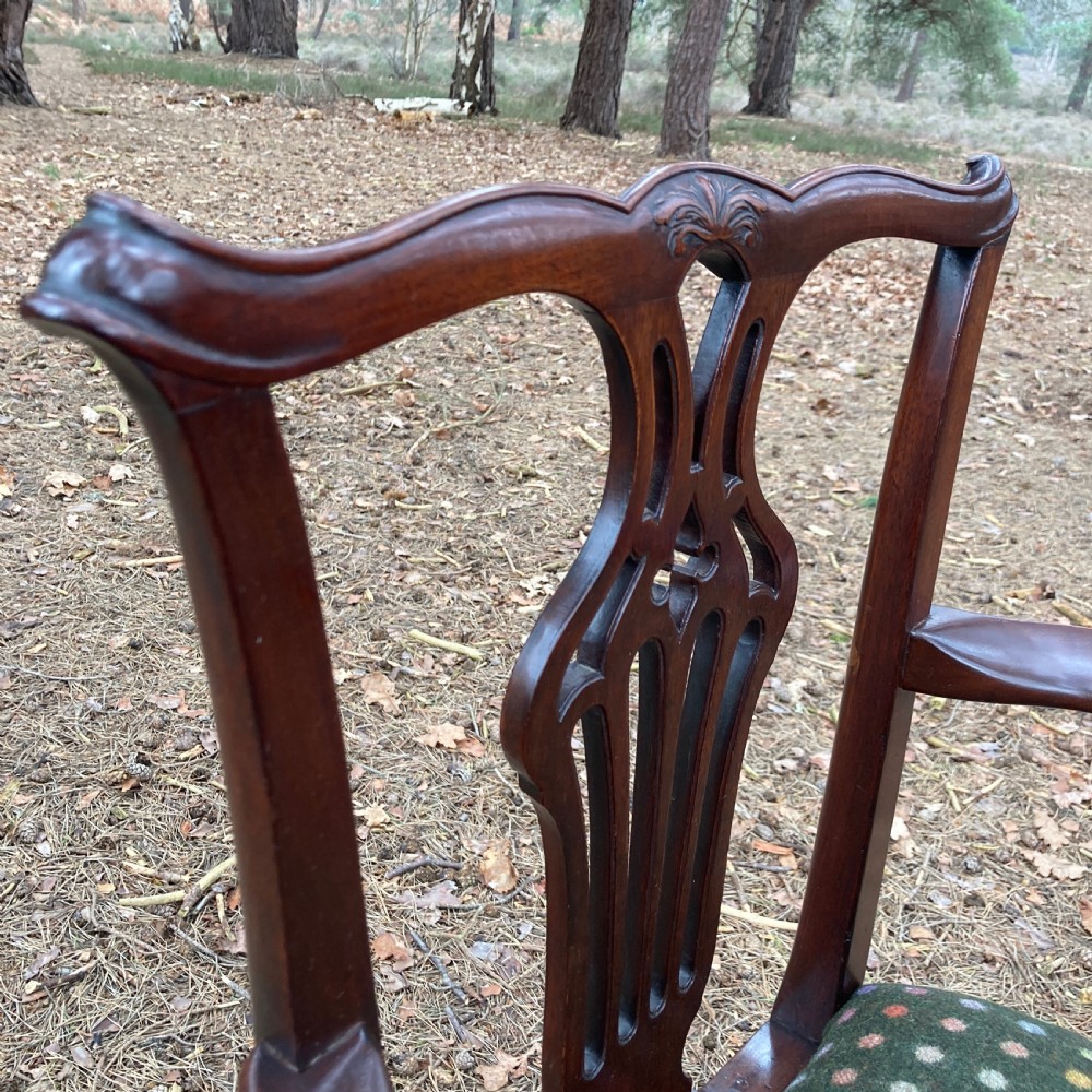 A pair of 1830s mahogany open armchairs featuring carved top rails, pierced splats, swept arms, and seats upholstered in a green patterned fabric. View XII