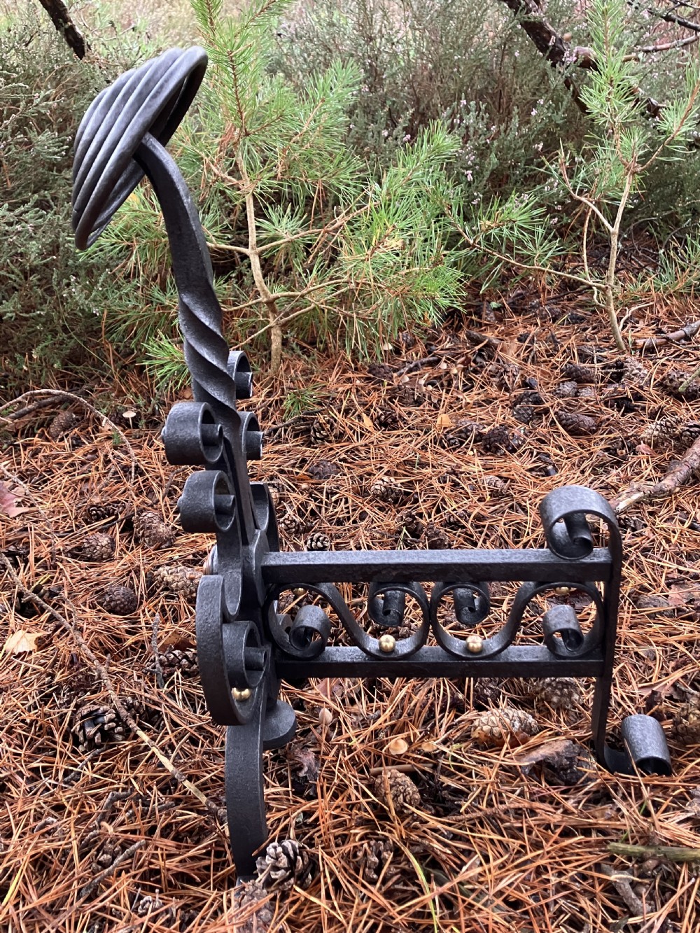 A pair of hand-forged black wrought iron fire dogs featuring spiral terminal tops, twisted stems, scrollwork bases, and copper boss accents. View VIII