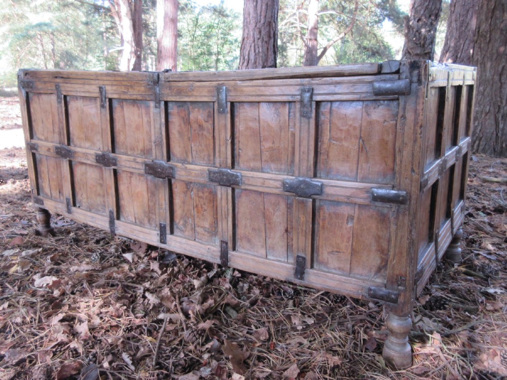 A large 19th-century Indian timber marriage chest featuring panelled sides, iron strapping, and turned feet.