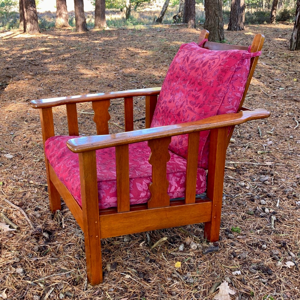 An Edwardian teak reclining armchair featuring slatted side panels, wide flat armrests, and pink floral upholstered cushions. View III