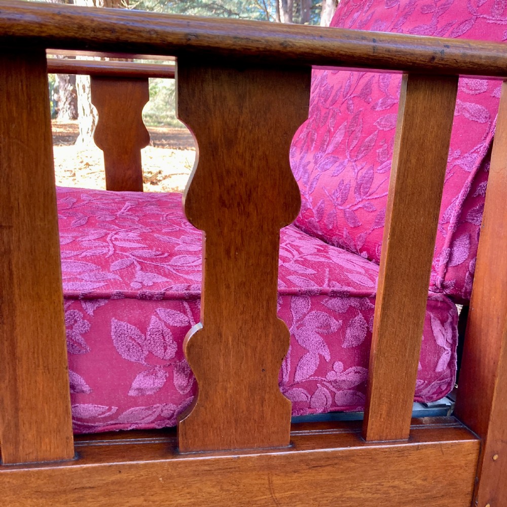 An Edwardian teak reclining armchair featuring slatted side panels, wide flat armrests, and pink floral upholstered cushions. View IX