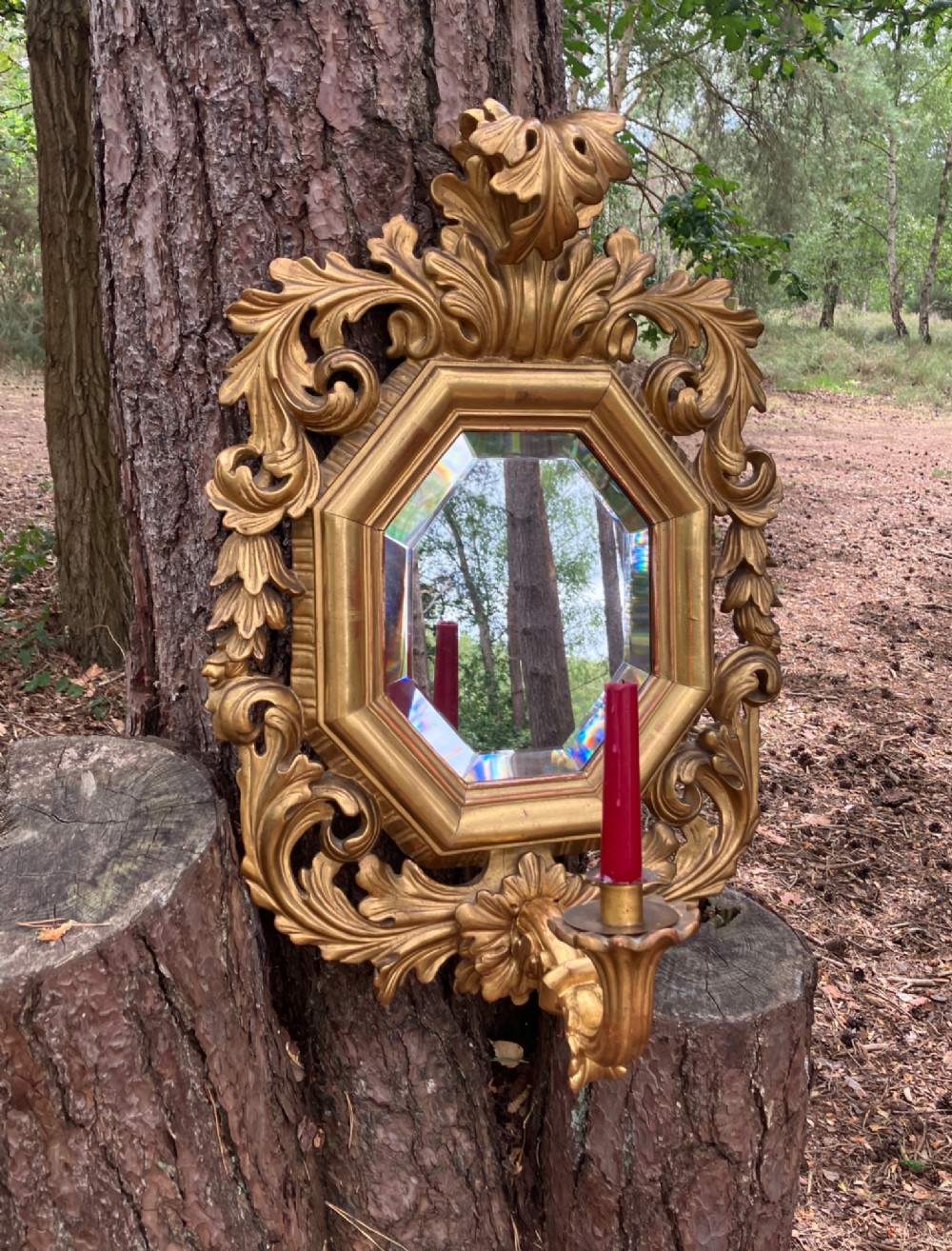 An octagonal 19th-century French giltwood girandole wall mirror featuring carved acanthus leaf motifs and an integrated central candle sconce holding a single candle. View IV