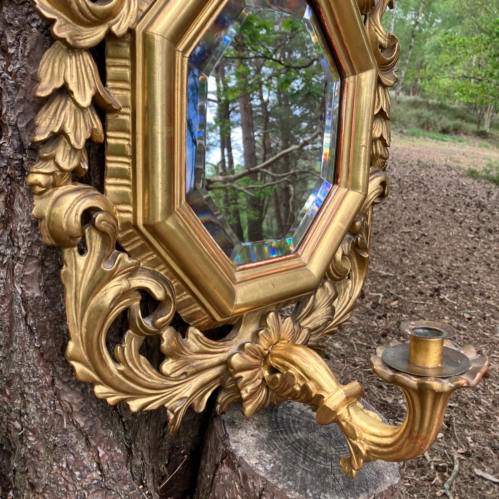 An octagonal 19th-century French giltwood girandole wall mirror featuring carved acanthus leaf motifs and an integrated central candle sconce holding a single candle. View VI