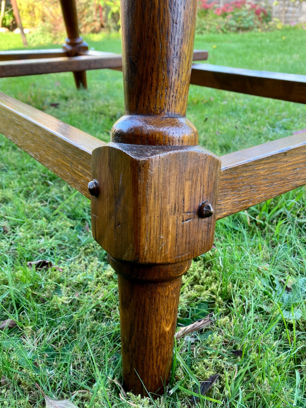 A solid medium oak Arts and Crafts refectory dining table with drop-leaf sides, turned angled legs, and a low stretcher base. View XI