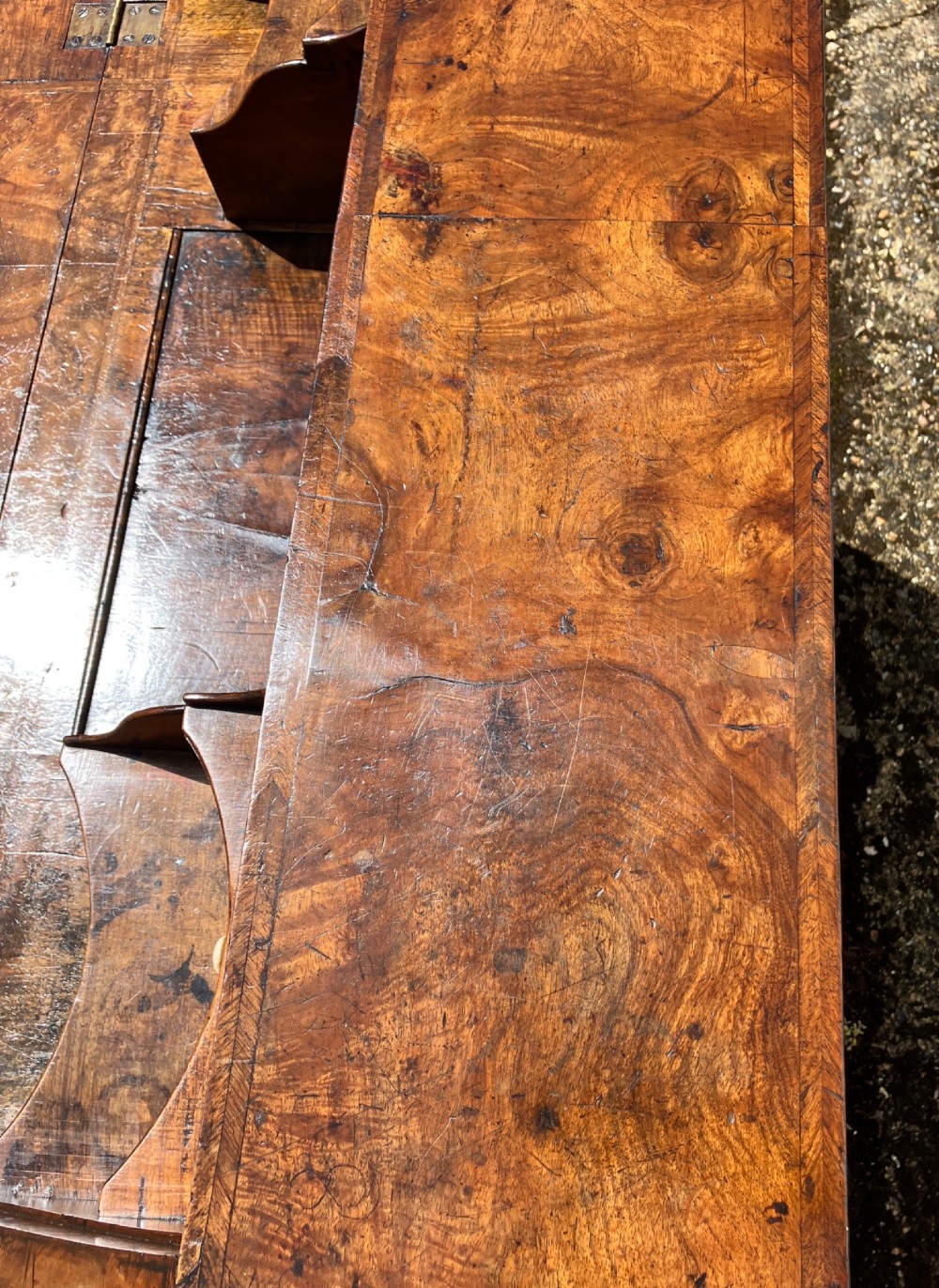 An early 18th-century English walnut fall front bureau featuring figured timber veneers, brass handles, and turned bun feet. View XI