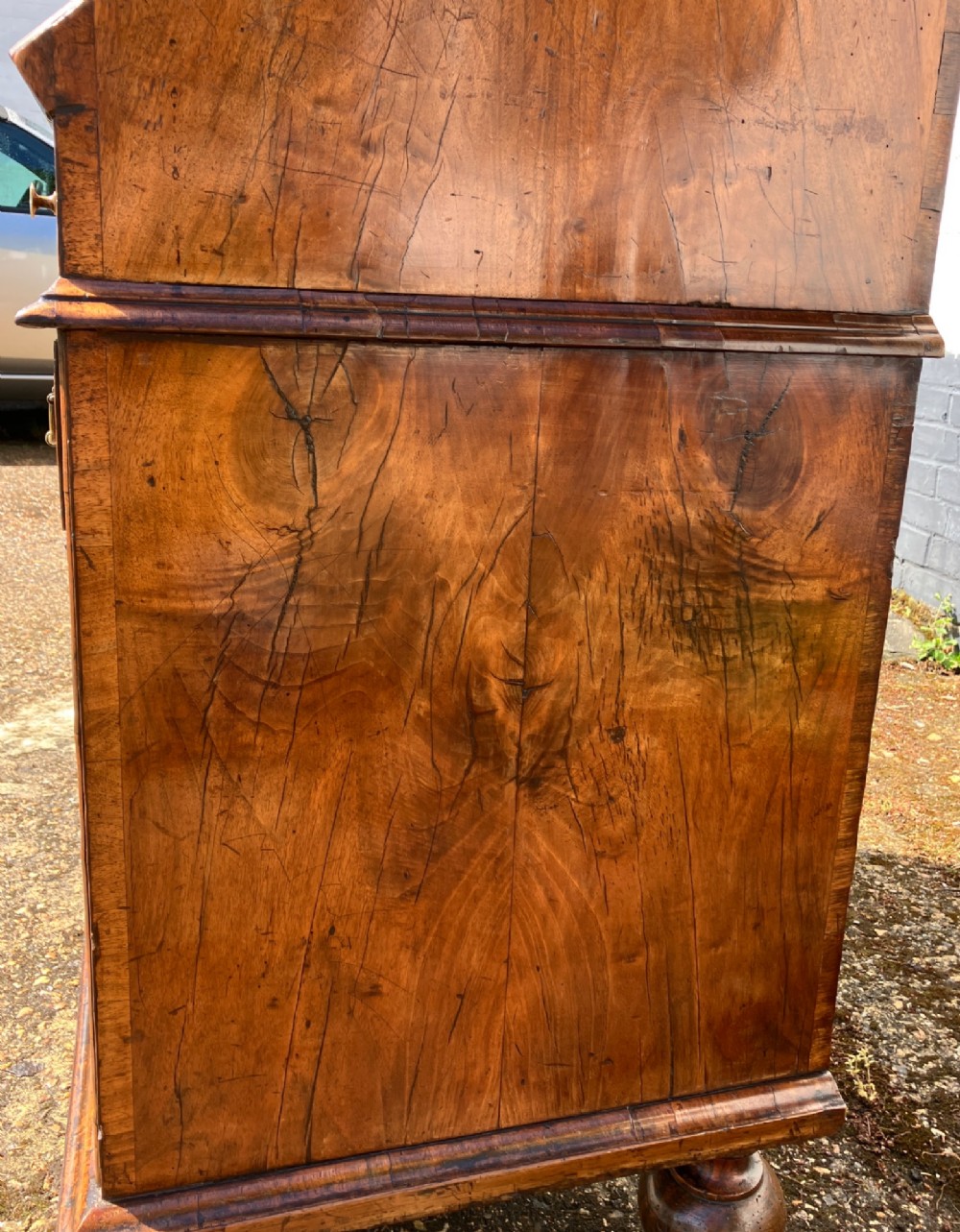 An early 18th-century English walnut fall front bureau featuring figured timber veneers, brass handles, and turned bun feet. View XII