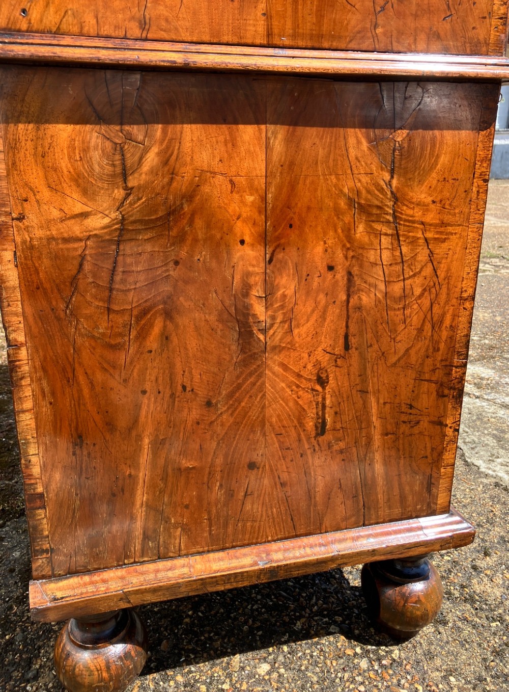 An early 18th-century English walnut fall front bureau featuring figured timber veneers, brass handles, and turned bun feet. View XIII