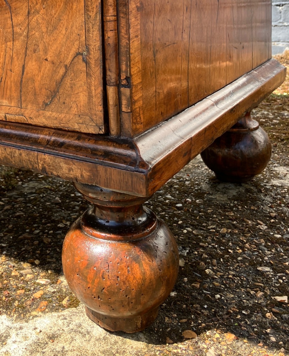 An early 18th-century English walnut fall front bureau featuring figured timber veneers, brass handles, and turned bun feet. View XIV