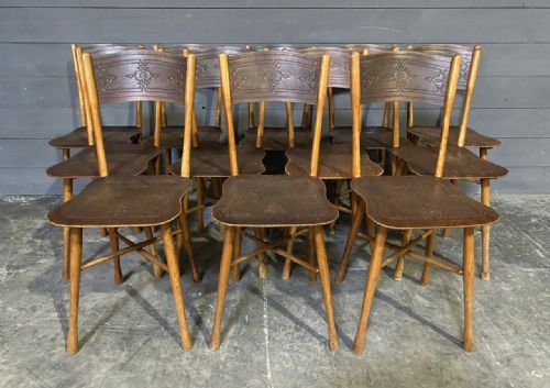 fig 1. A set of twelve dark brown antique bentwood side chairs featuring embossed floral pattern seats and curved backrests.