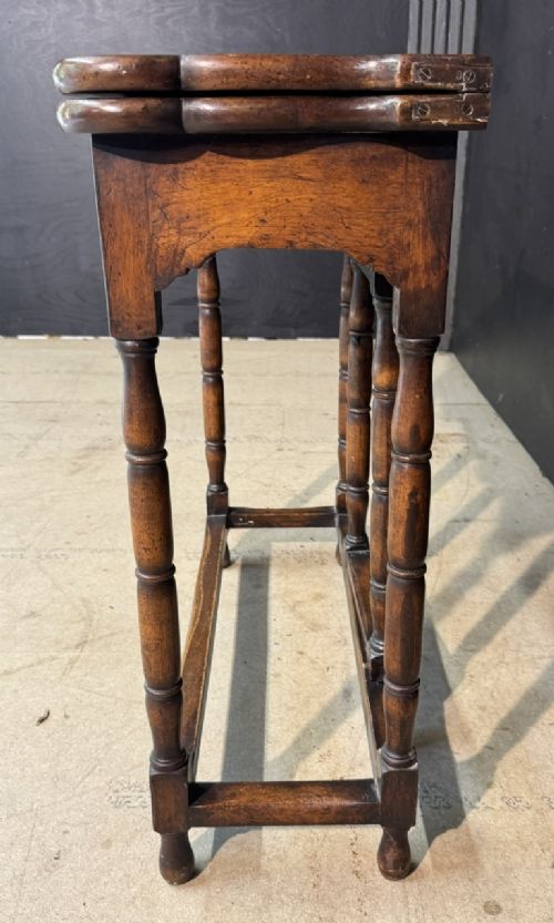 An antique walnut fold-over tea table with a shaped double top, contoured frieze, turned legs, and a lower box stretcher. View XI