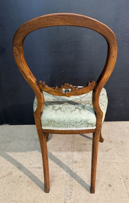 A Victorian balloon back side chair featuring a carved warm brown wood frame, cabriole front legs, and a sage green damask upholstered seat. View VI