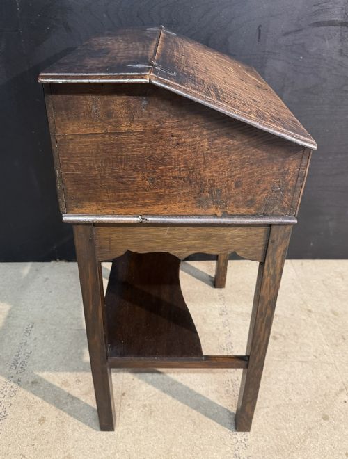 A 17th-century dark oak writing slope box on a wooden stand, featuring carved initials R S and a central iron lock plate. View IX