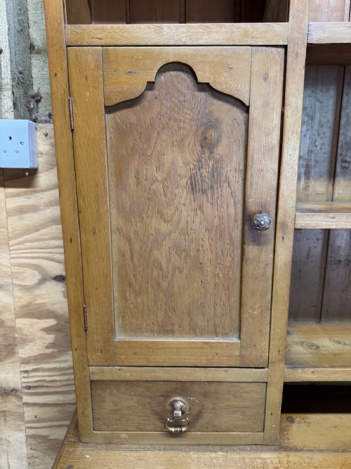 A two-part antique pine Welsh dresser featuring an open plate rack flanked by small side cupboards above three frieze drawers and an open pot board base. View XII