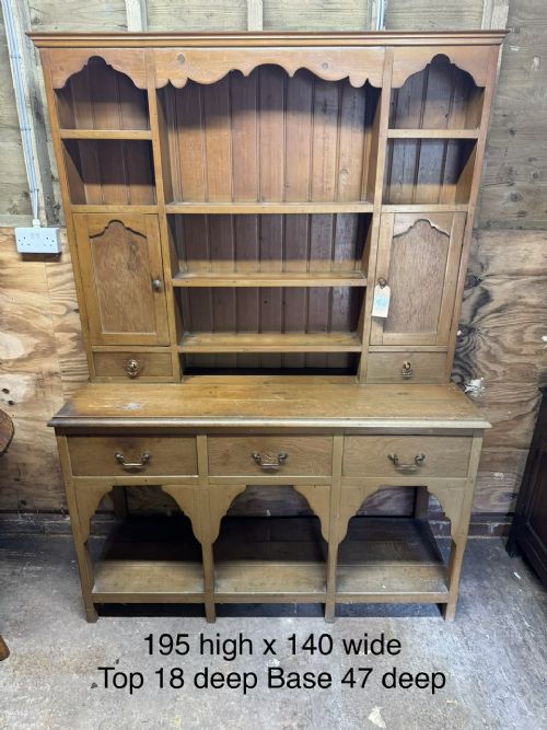 A two-part antique pine Welsh dresser featuring an open plate rack flanked by small side cupboards above three frieze drawers and an open pot board base. View XV