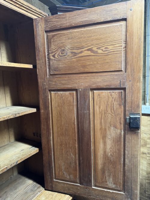 A two-tier nineteenth-century pine school cabinet featuring panelled double doors, brass catches, and a natural waxed finish. View VII
