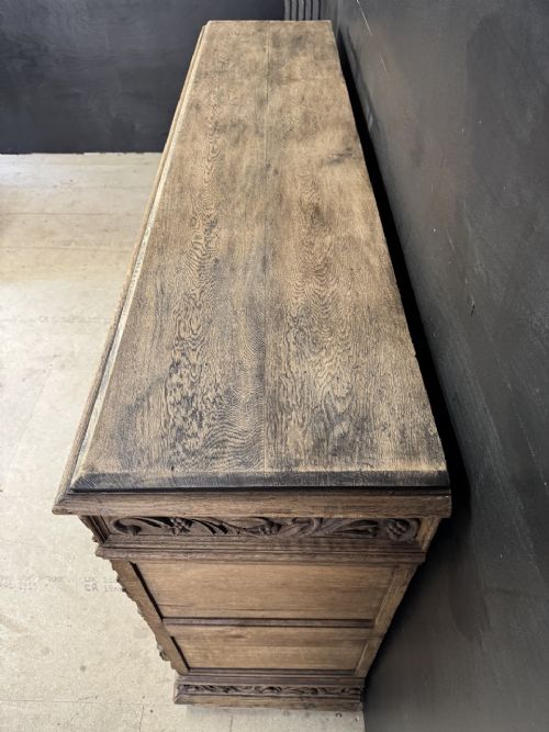 A three-door carved light oak sideboard featuring detailed relief panels depicting artistic and musical instruments. View II