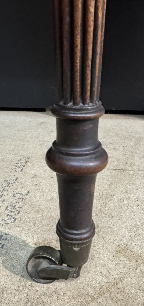 A Georgian style dark mahogany sofa table featuring two drawers with brass ring pulls, drop leaves on either side, and reeded tapered legs on brass castors. View IX