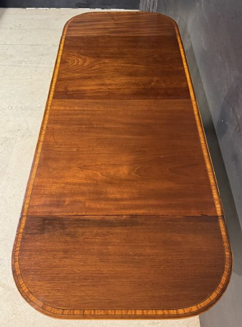 A Georgian mahogany sofa table featuring two inline drawers with satinwood string inlay, drop leaves, twin-pillar supports, and splayed legs ending in brass claw feet on castors. View VI