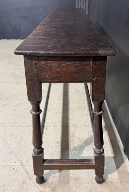 A long dark oak Georgian joint stool with turned legs, a rectangular top, and lower wooden stretchers. View VI